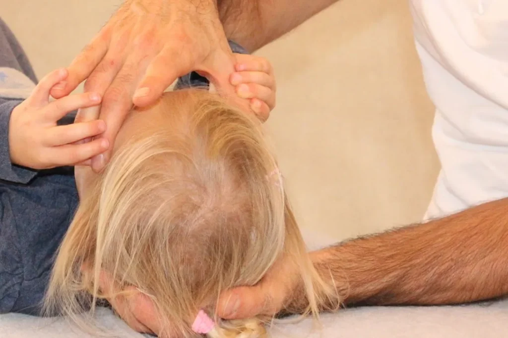 Osteopathische Behandlung: Hände halten sanft den Kopf eines Kindes